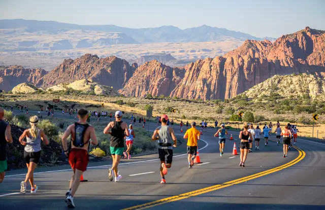 Runners descending through red rock formations at the St. George Marathon